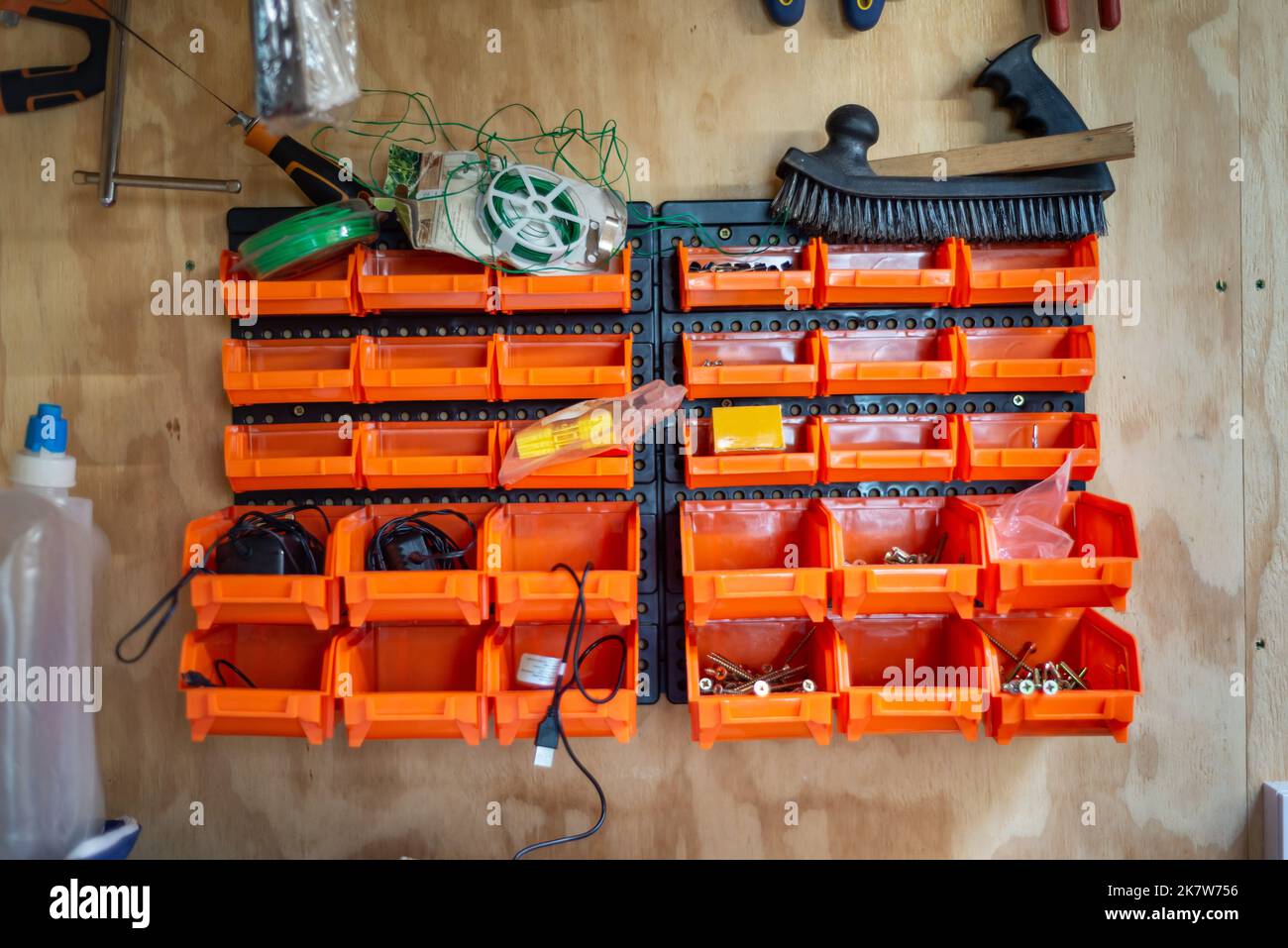 Appendiabiti a parete, capannone per utensili, scaffale in plastica per organizer. Colore arancione sulle pareti di legno. Foto Stock