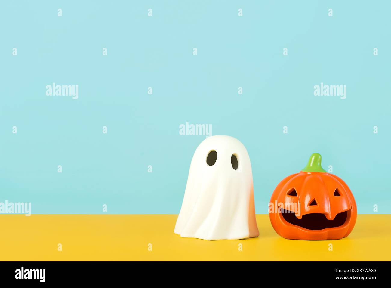 Halloween felice. Divertente zucca di Halloween e fantasma di Halloween con spazio di copia su sfondo giallo e blu Foto Stock