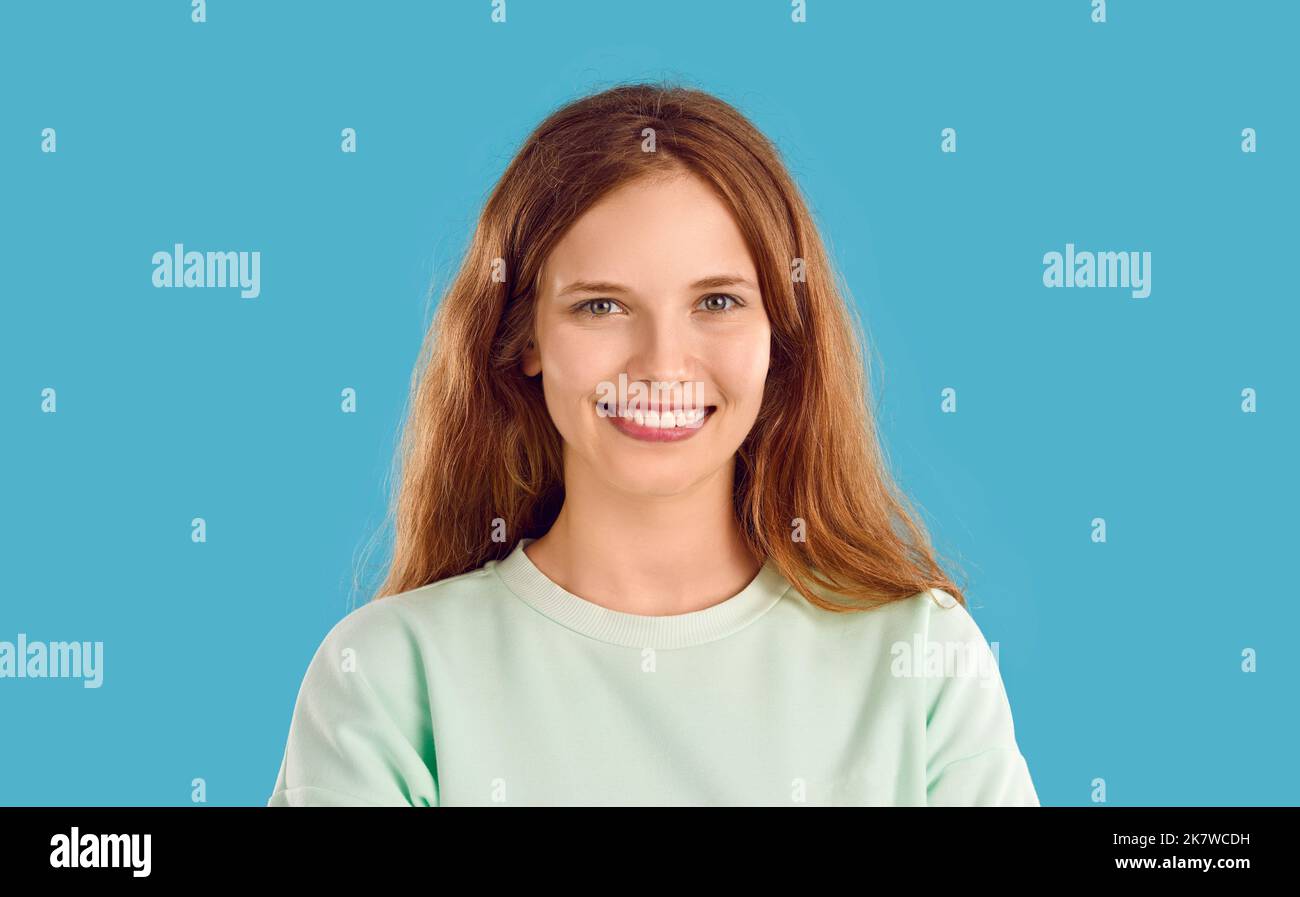 Giovane donna sorridente felice in felpa di menta sta posando su sfondo blu guardando la macchina fotografica. Foto Stock