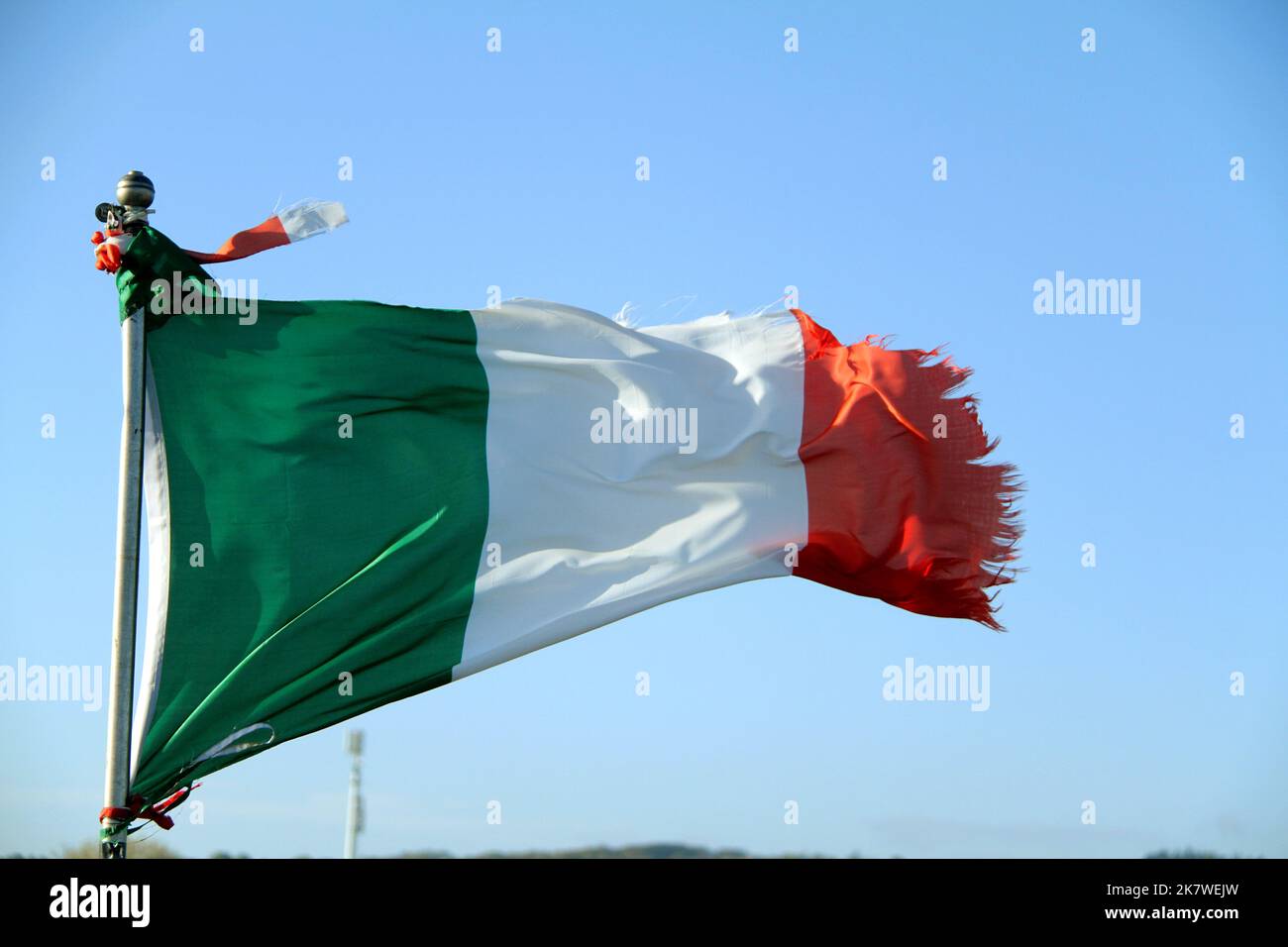 Bandiera italiana ondulata danneggiata da forti venti Foto Stock