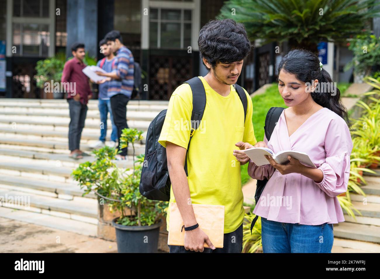 Seri ragazzi indiani che si preparano per gli esami leggendo libri al campus universitario - concetto di conoscenza, istruzione e concorrenza Foto Stock