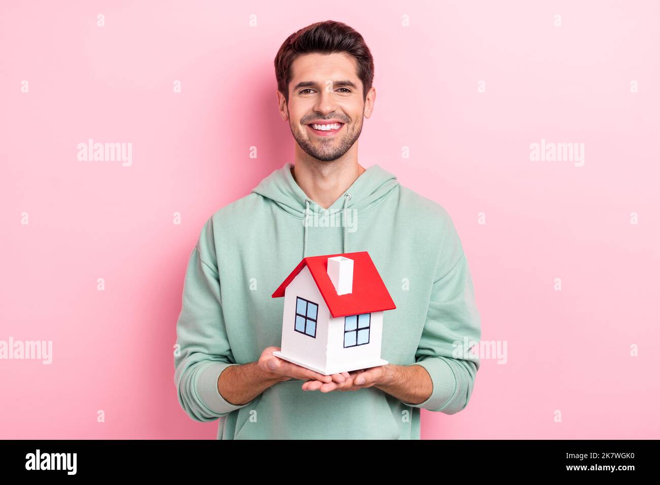 Foto di persona positiva braccia tenere piccola casa toothy sorriso isolato su sfondo di colore rosa Foto Stock