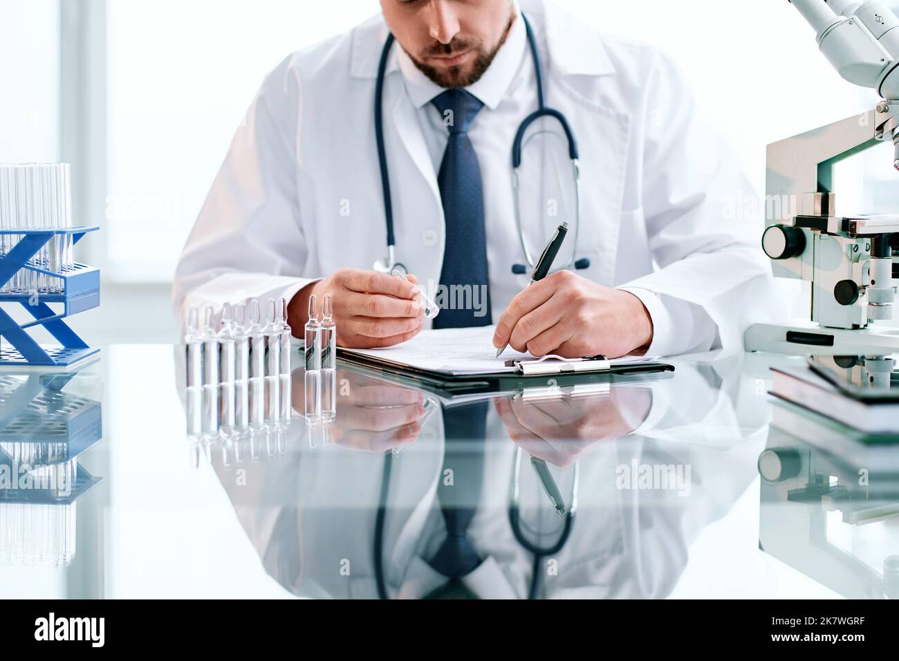 lo scienziato prende appunti mentre lavora in un laboratorio clinico. Foto Stock