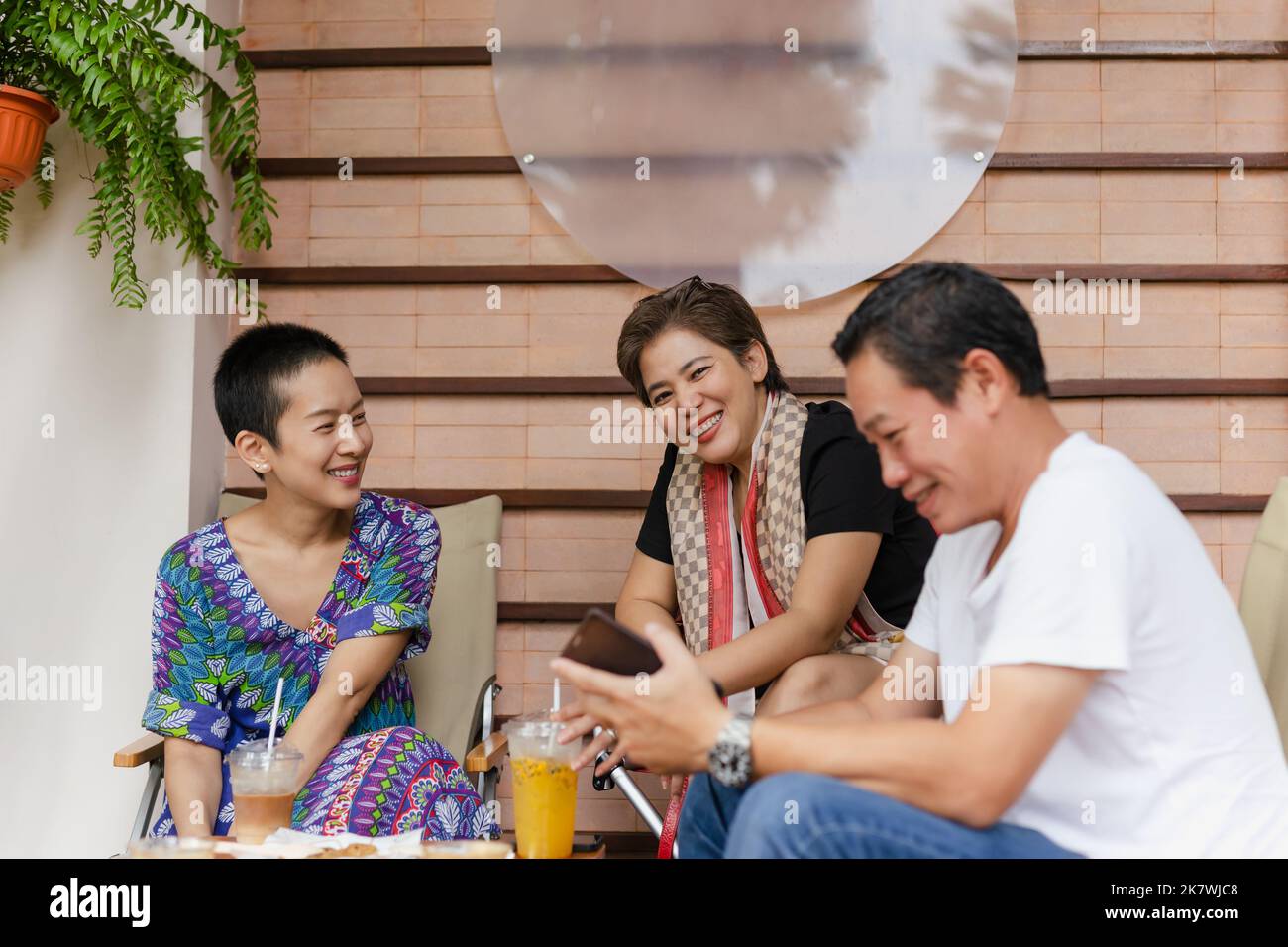 Gli amici si divertono sorridendo e bevendo caffè e succo di frutta nel bar. Foto Stock