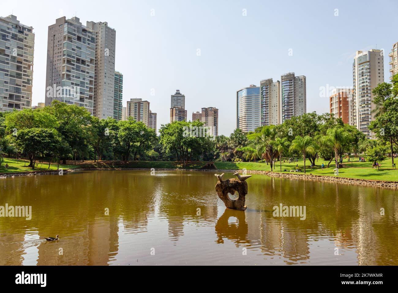 Goiânia, Goias, Brasile – 18 ottobre 2022: Un angolo del Parco Flamboyant, che mostra il lago, gli alberi, gli edifici e il cielo blu sullo sfondo. Foto Stock