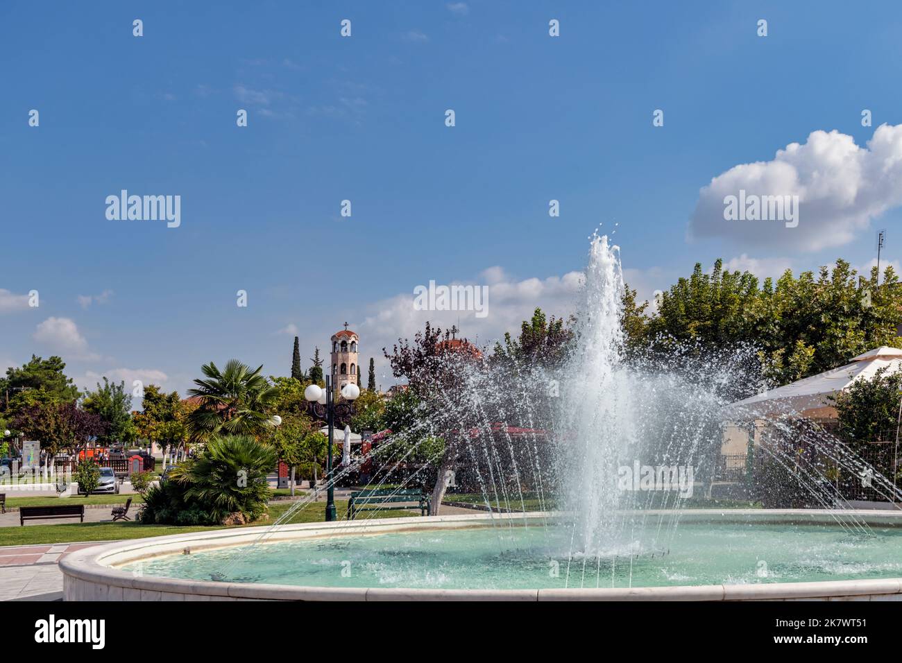 Springbrunnen im Park von Agios Athanasios in Griechenland mit Kirche im Hintergrund Foto Stock