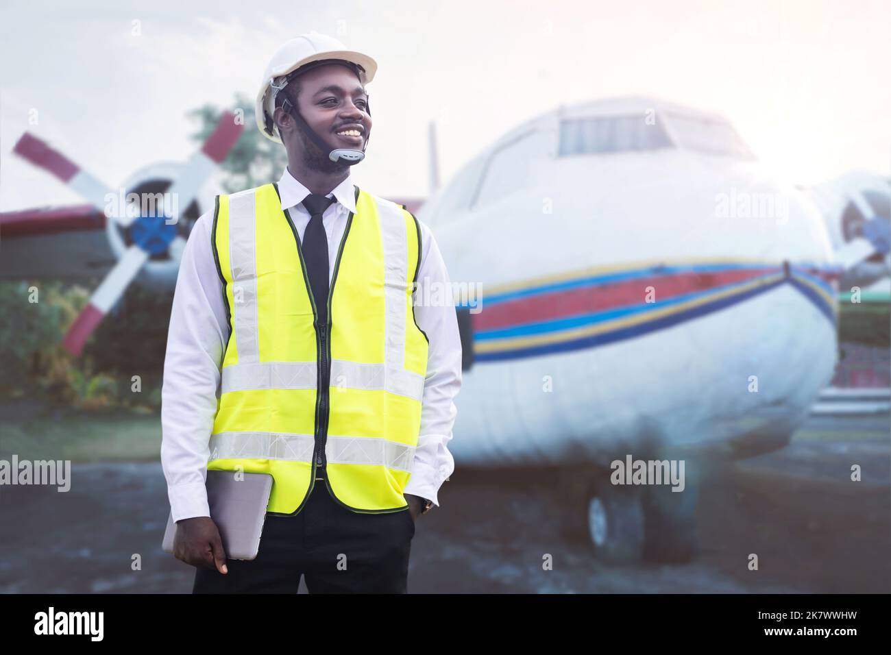 Ingegnere africano uomo, tecnico che controlla e ripara motore di aereo con tablet in mano Foto Stock