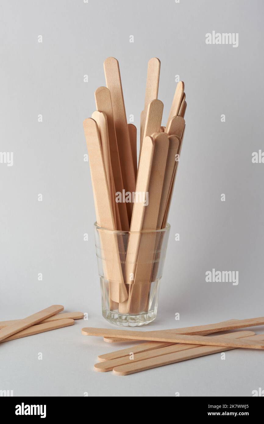 primo piano del gelato di legno si stacca su un bicchiere e sparso su sfondo grigio neutro Foto Stock