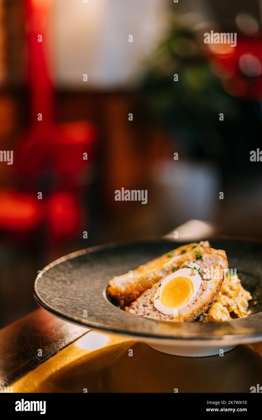 Tradizionale 'uovo di Scotch'. 'Skirly' è la farina d'avena fritta con cipolle e spezie, una decorazione classica della Scozia. Salsa di senape al miele. Piatto tradizionale di Foto Stock