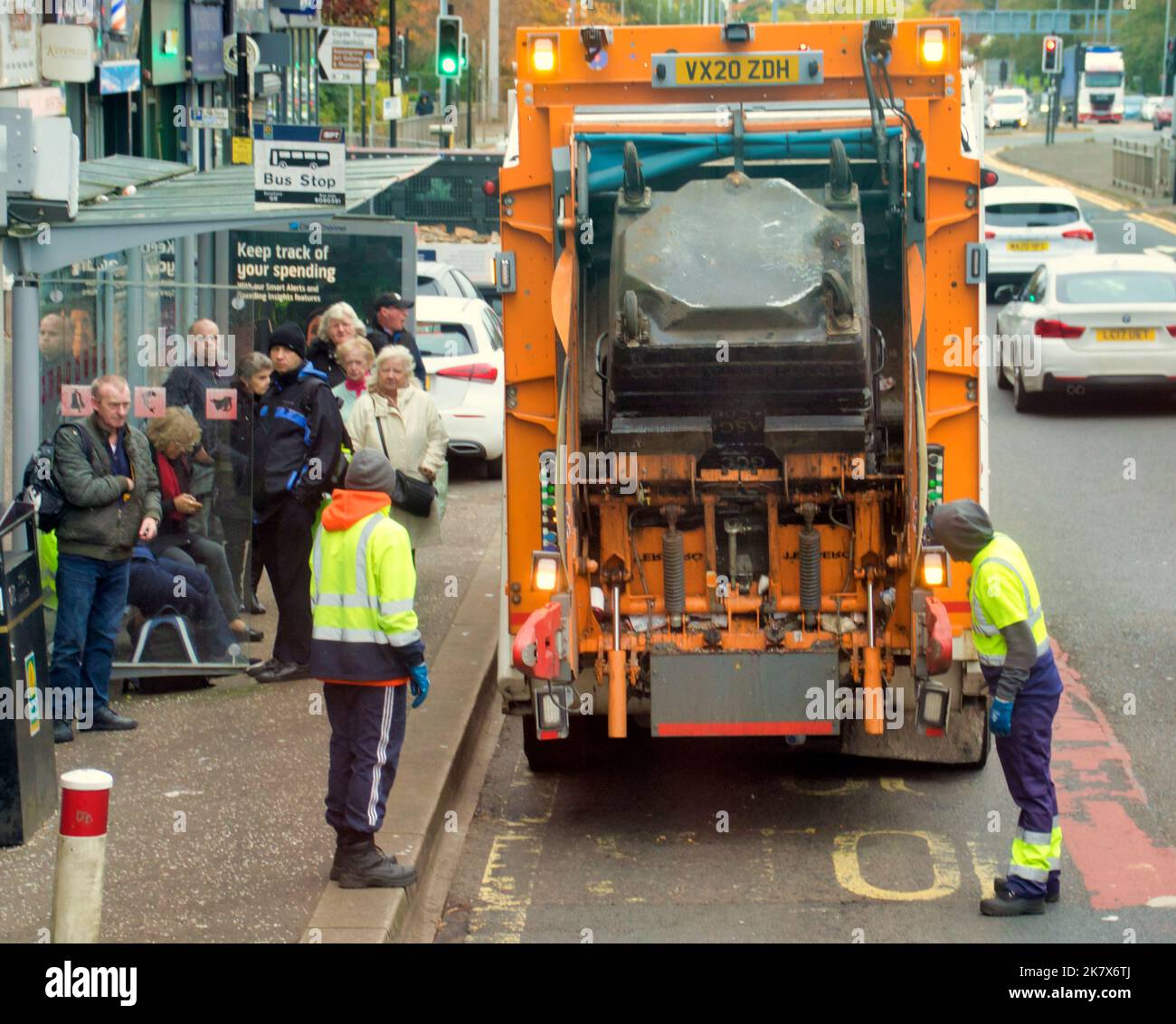 carretto per la polvere e binmen che caricano davanti alla fermata dell'autobus Foto Stock