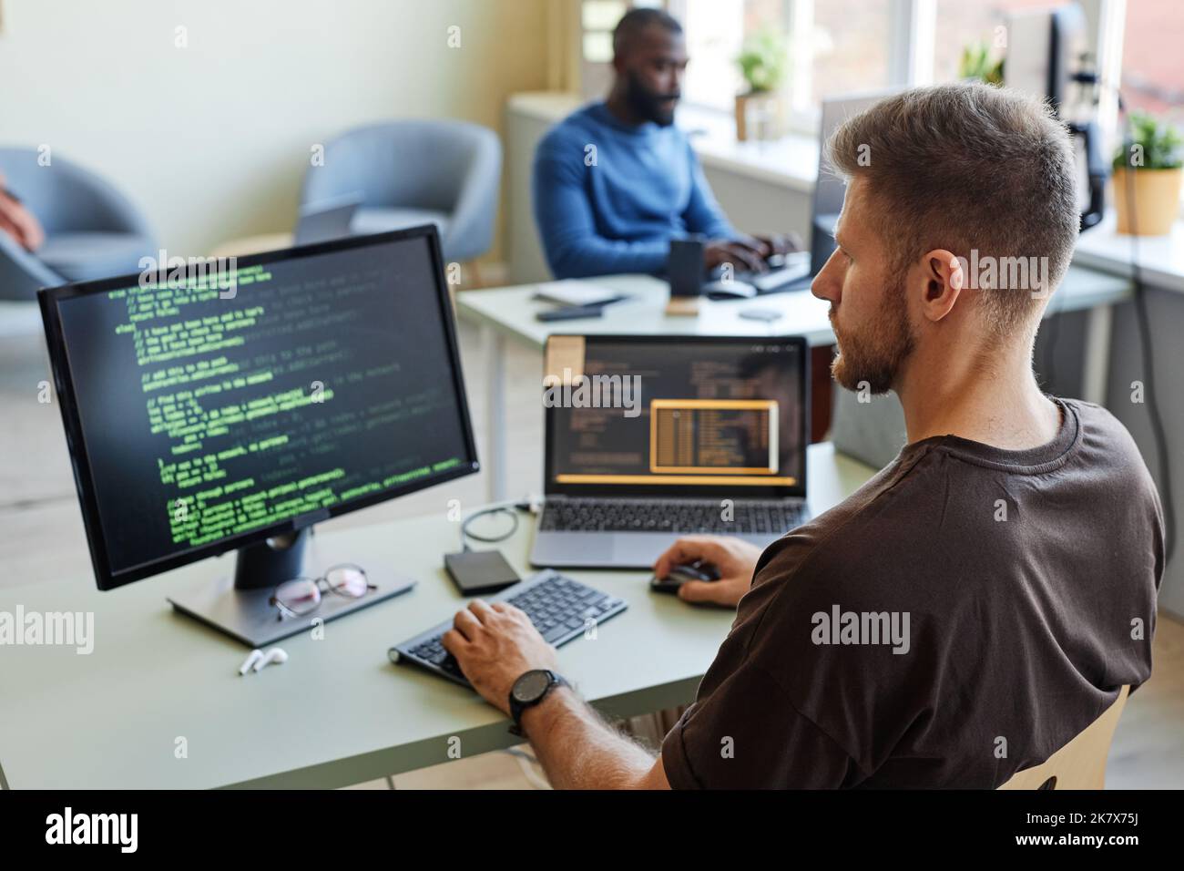 Ritratto del software engineer che scrive codice sul luogo di lavoro in ufficio con più dispositivi Foto Stock