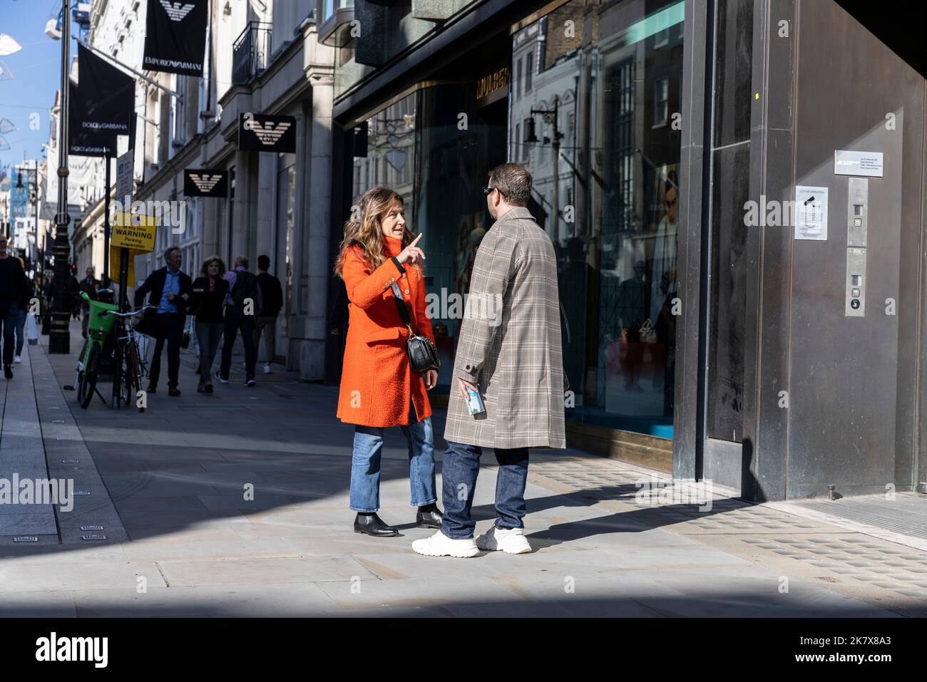Una coppia che tiene una conversazione mentre si trova su Old Bond Street, nel centro di Londra, Inghilterra, Regno Unito Foto Stock