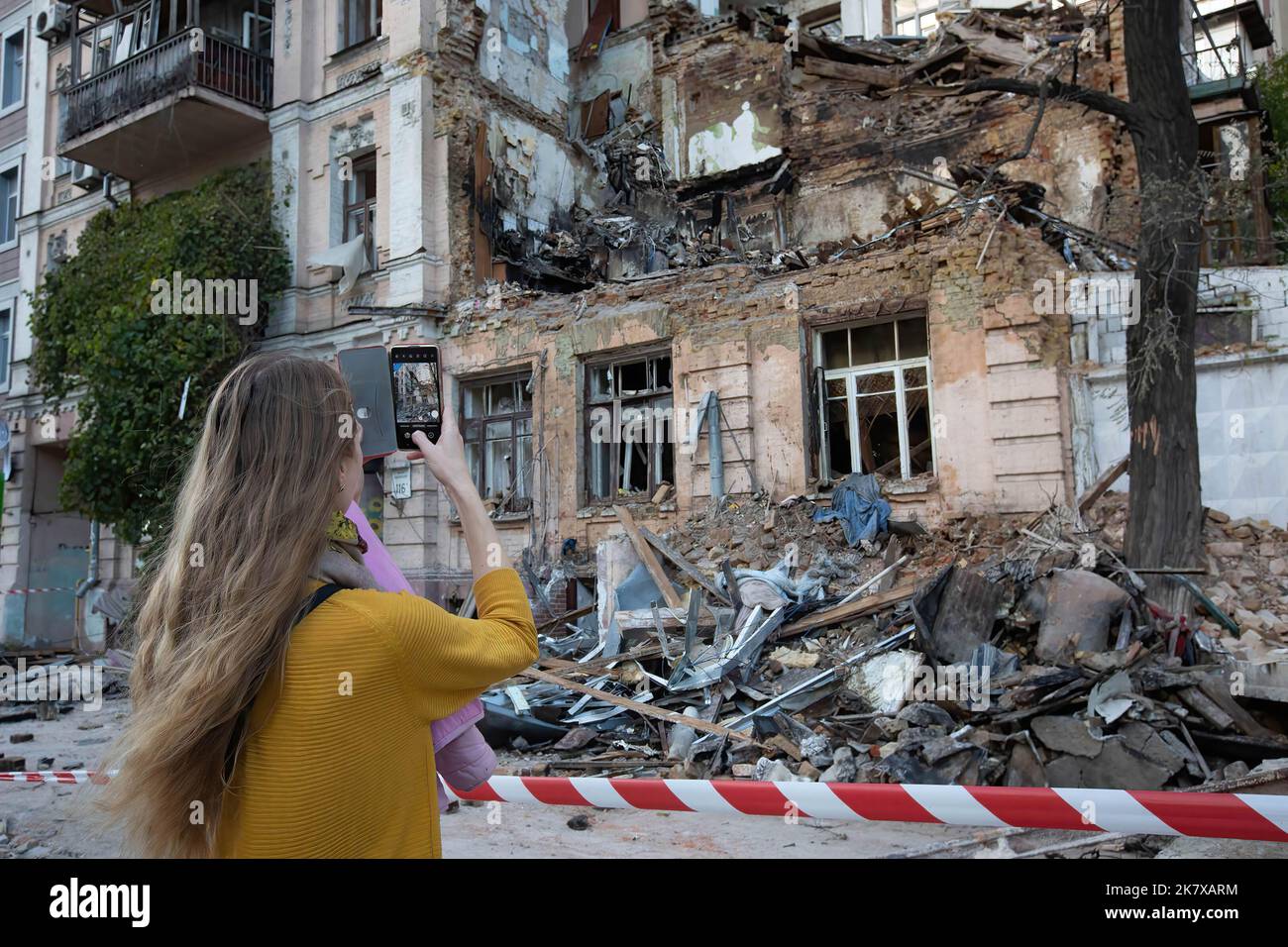 Una ragazza scatta una foto di un edificio residenziale distrutto da uno sciopero di droni russi, che le autorità locali considerano come veicoli aerei senza equipaggio (UAV) Shahed-136 di produzione iraniana, nel centro di Kyiv. Almeno quattro persone sono state uccise a seguito di un attacco di droni contro un edificio residenziale a Kiev la mattina del 17 ottobre 2022. Foto Stock