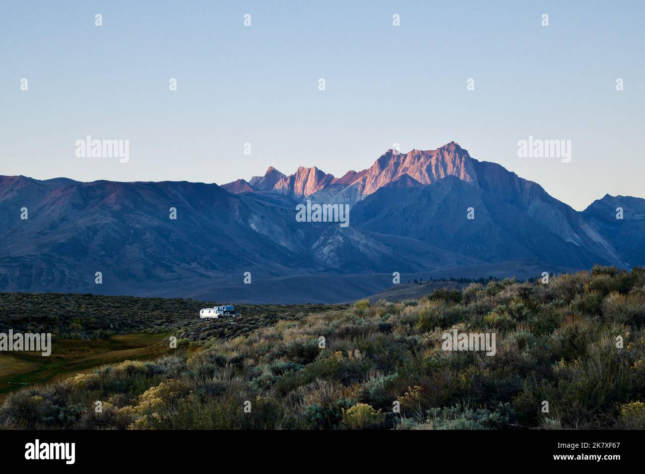Luce dell'alba che illumina un'aspra cima di montagna nella Sierra Nevada orientale con il deserto in primo piano Foto Stock