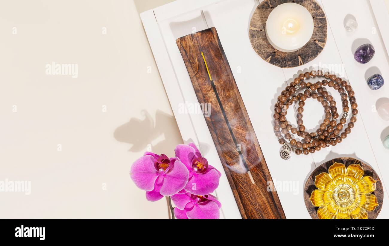 Perline di Rosario, candele, bastoncini aromatici, pietre di chakra e orchidee con spazio copia Foto Stock