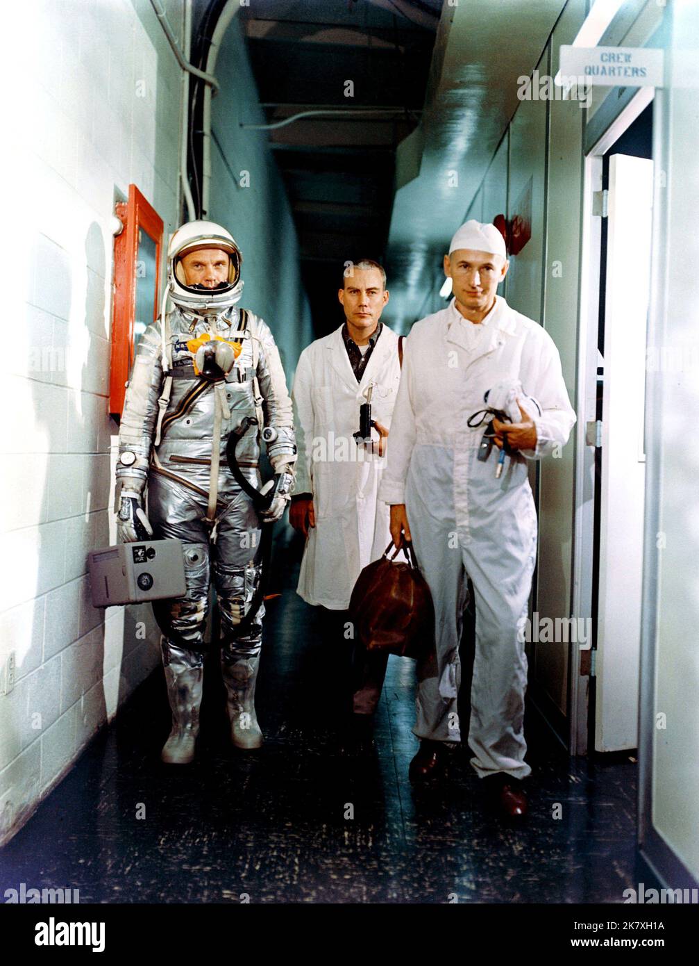 L'astronauta John H. Glenn Jr. (A sinistra); il Dott. William Douglas, chirurgo di volo degli astronauti; e lo specialista di attrezzature Joe Schmitt lasciano i quartieri dell'equipaggio prima della missione Mercury-Atlas 6 (ma-6). Glenn è nella sua tuta a pressione e sta trasportando l'unità di ventilazione portatile. Foto Stock
