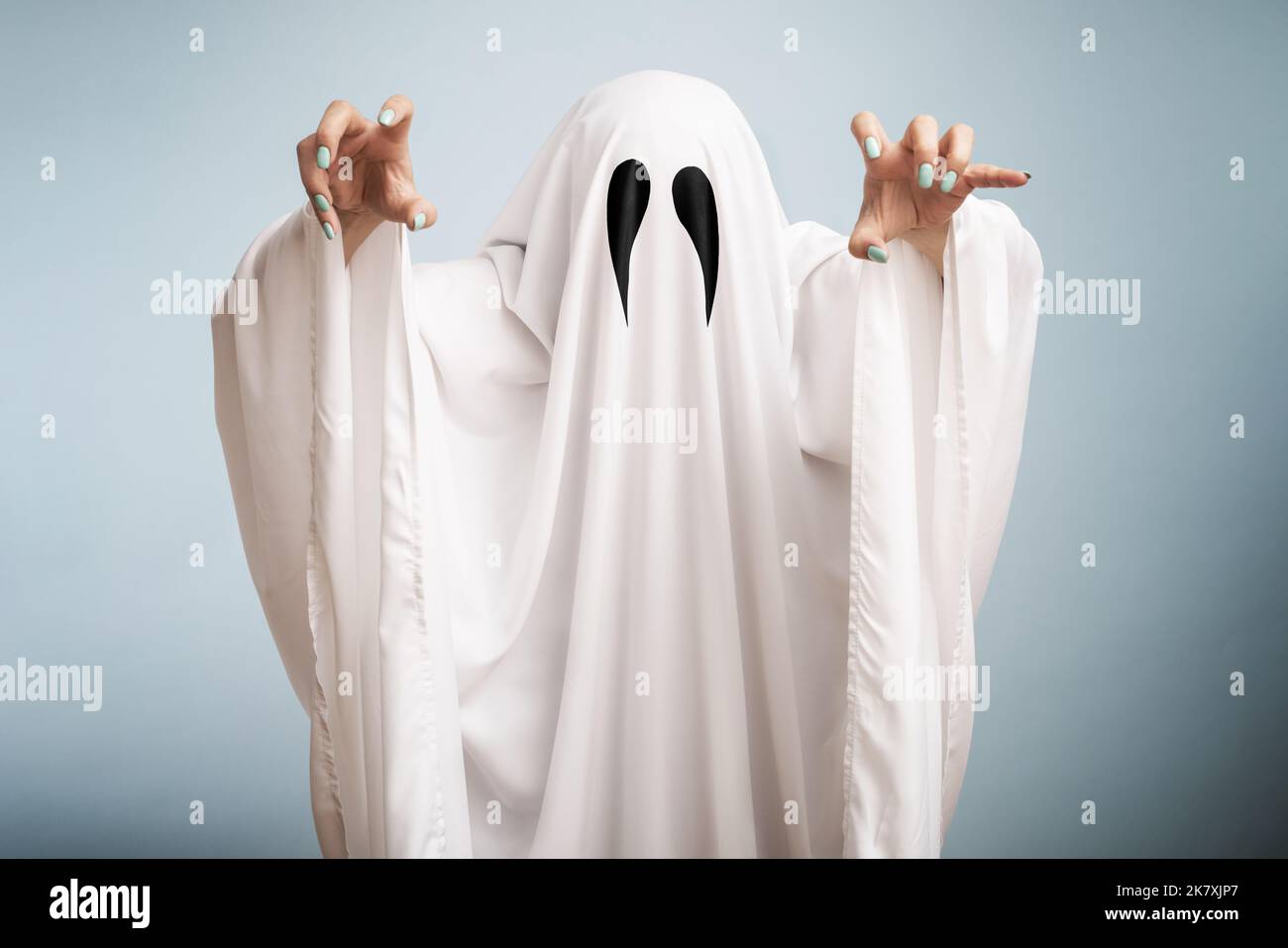 Concetto di Halloween. Un fantasma bianco con occhi neri, realizzato da un lenzuolo su sfondo blu Foto Stock