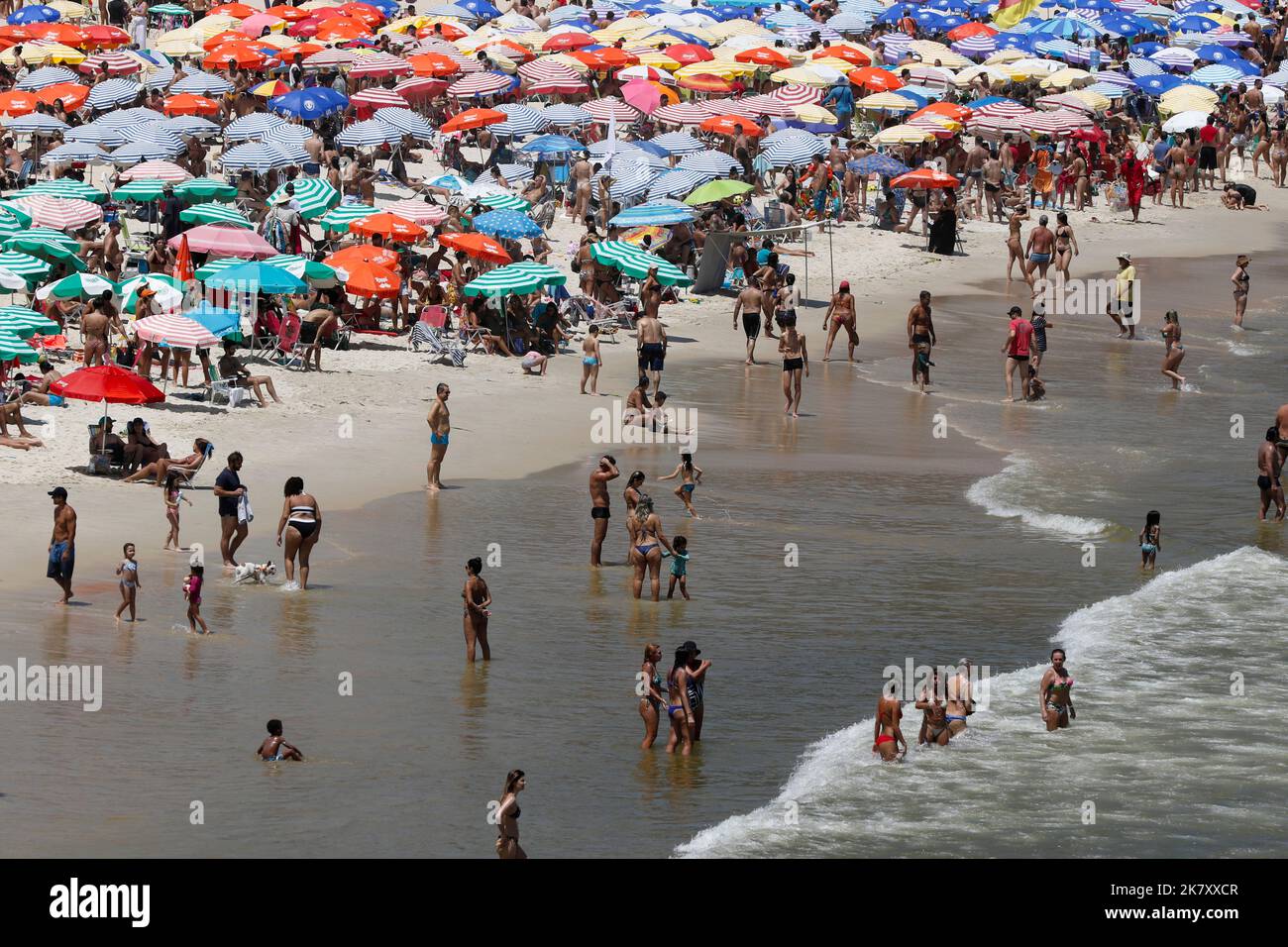 Spiaggia di Leblon, Rio de Janeiro, Brasile. Persone che prendono il sole vicino alla spiaggia con ombrelloni colorati. La folla può godersi una giornata estiva nuotando in mare. Viaggio tropicale Foto Stock