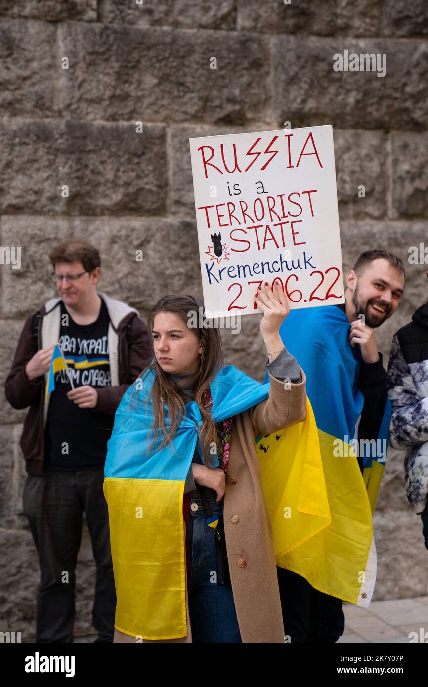 Birmingham, Regno Unito. 15th Ott 2022. Sostenitori ucraini che manifestano contro RussiaÕs invasione e occupazione dell'Ucraina al di fuori del Municipio di Birmingham, West Midlands, Regno Unito. Ragazza con bandiera drappeggiata sulle spalle, tenendo ÔRussia è uno stato terroristico, KremenchukÕ poster. Credito: NexusPix/Alamy Foto Stock