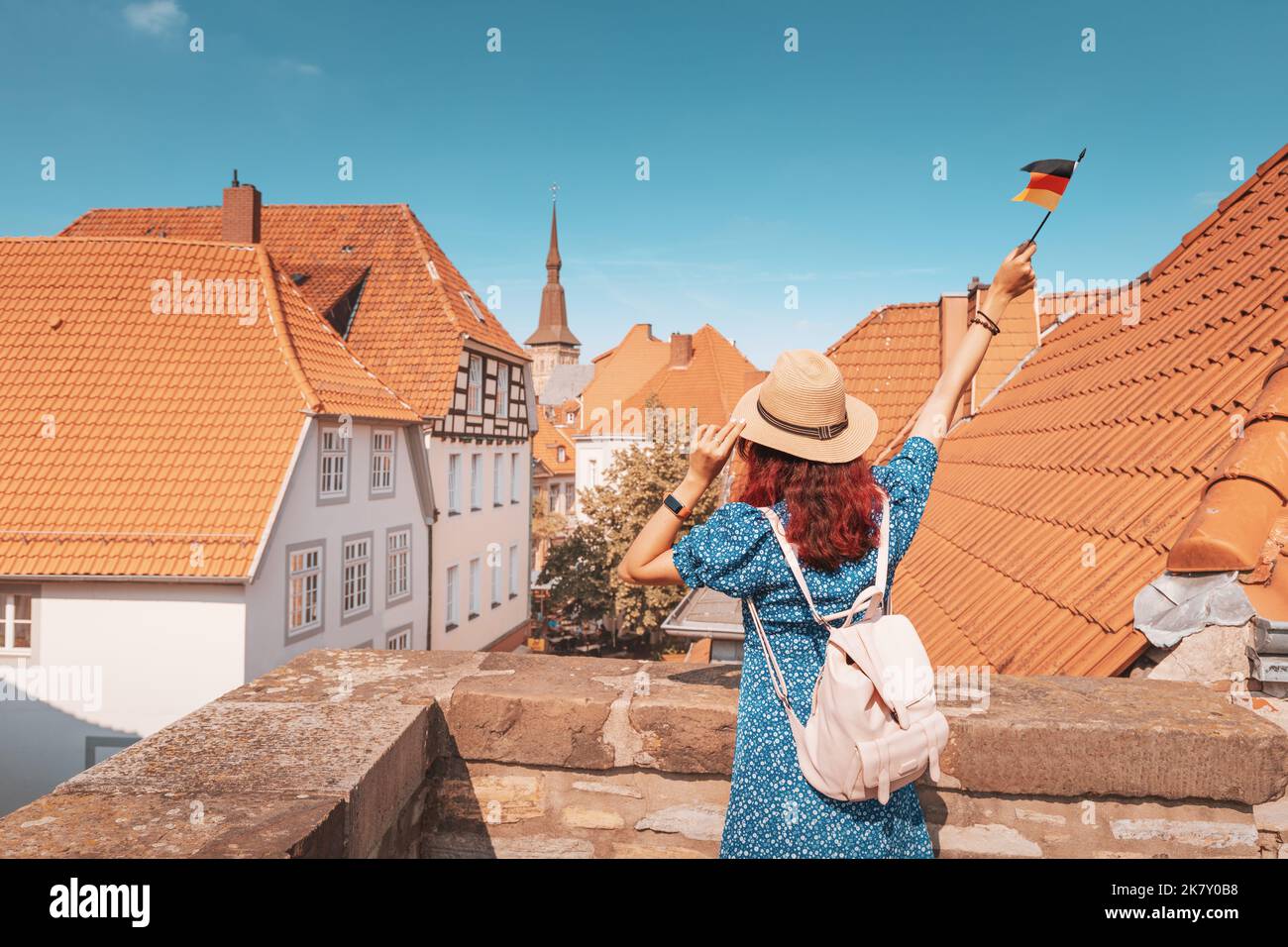 Una giovane ragazza asiatica felice con una bandiera tedesca nella città vecchia o punto di osservazione Altstadt a Osnabruck. Studiare la lingua all'estero e il concetto di viaggio Foto Stock