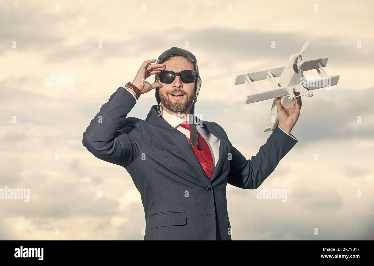 uomo d'affari allegro in abito e cappello pilota lancio aereo giocattolo Foto Stock
