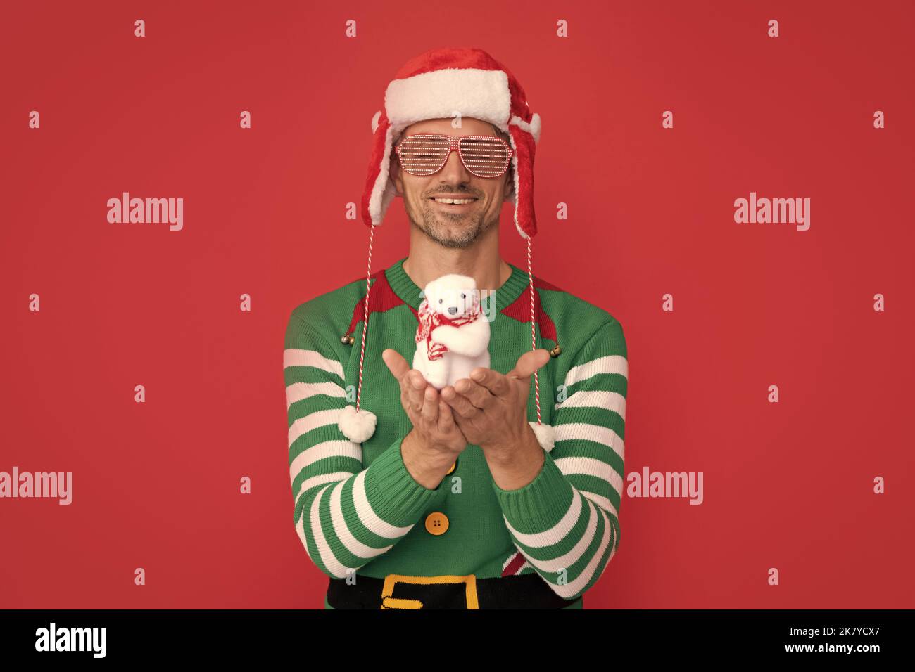 buon natale. uomo felice in costume di elfo e cappello di babbo natale. ragazzo in occhiali che mostrano decorazione Foto Stock