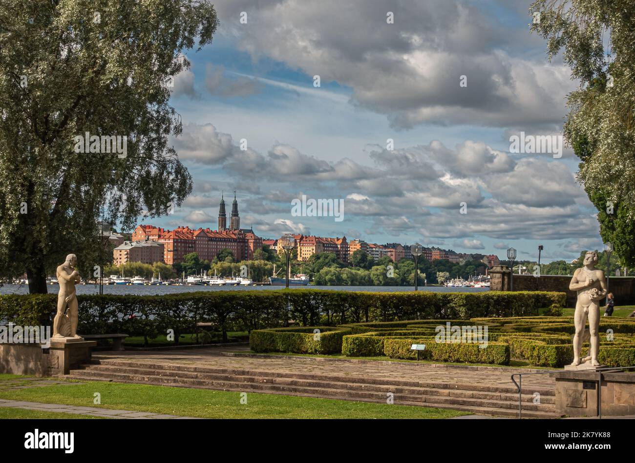 Svezia, Stoccolma - 16 luglio 2022: Municipio o giardino Stadshuset, lato ovest con 2 statue maschili di pietra. La chiesa di Hogalid sovrasta gli edifici a sud Foto Stock
