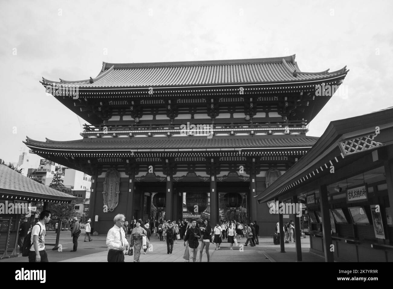 Vista della porta di Hozomon all'interno del complesso del tempio di Sensoji con folla di persone che camminano e nuvole sullo sfondo del cielo luminoso. Colore bianco e nero. Foto Stock