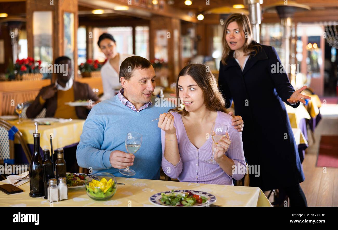 Donna stupita guardando il marito che mangiava con la sua padrona Foto Stock