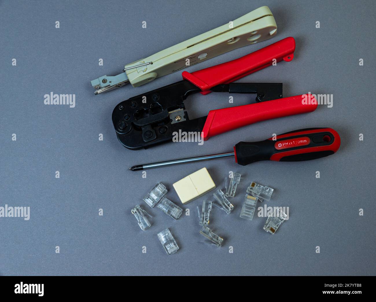 Pinza manuale a crimpare per la crimpatura dei terminali rotondi e un piccolo mucchio di terminali isolati blu su sfondo bianco Foto Stock