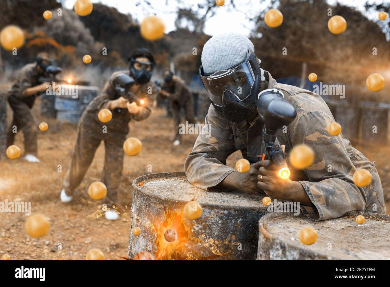 Giocatore di paintball americano africano che mira e spara con la pistola alla squadra avversaria Foto Stock