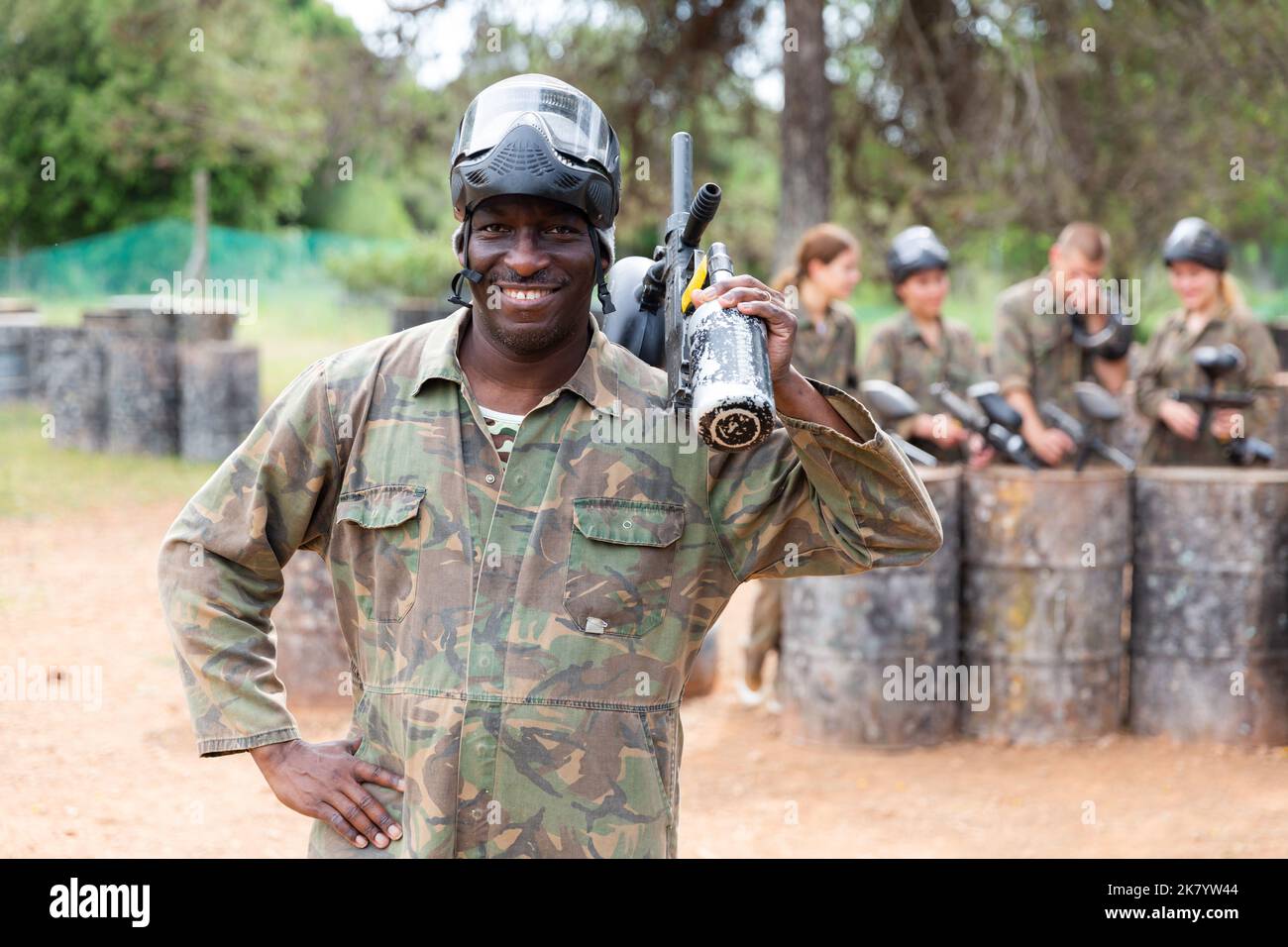 Ritratto di paintball giocatore in camouflage e maschera protettiva in piedi con pistola dopo paintball match Foto Stock