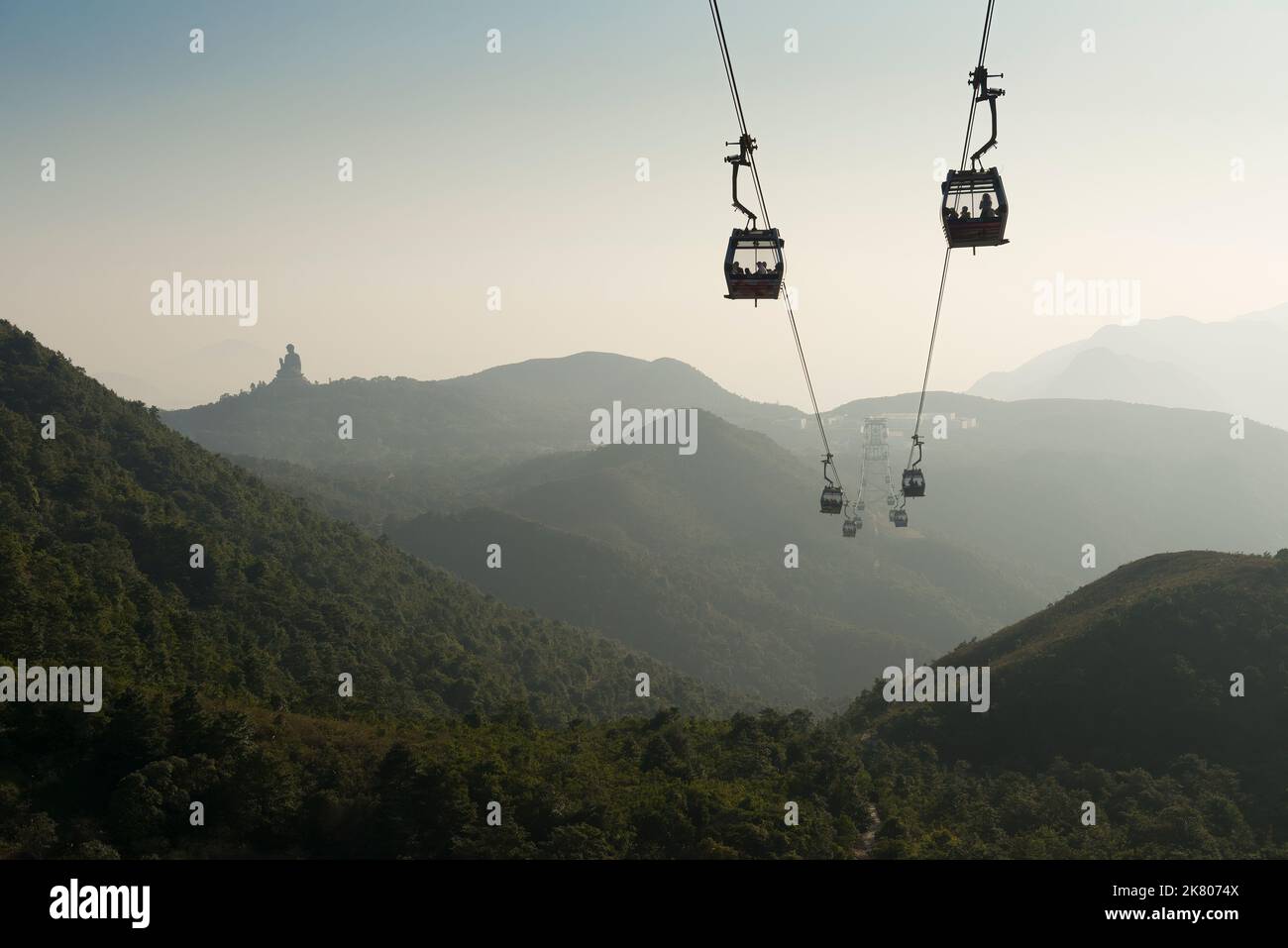 Una cabinovia porta i turisti al Villaggio di Ngong Ping e al Grande Buddha, visibile all'orizzonte in una giornata di nebbia, l'Isola di Lantau, Hong Kong Foto Stock