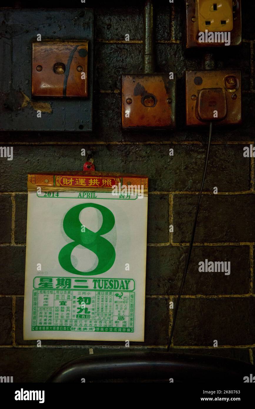 Dettaglio di un calendario, prese di corrente e interruttori macchiati da anni di fumo di incenso, nel tempio di Tin Hau, Yau ma Tei, Kowloon, Hong Kong Foto Stock