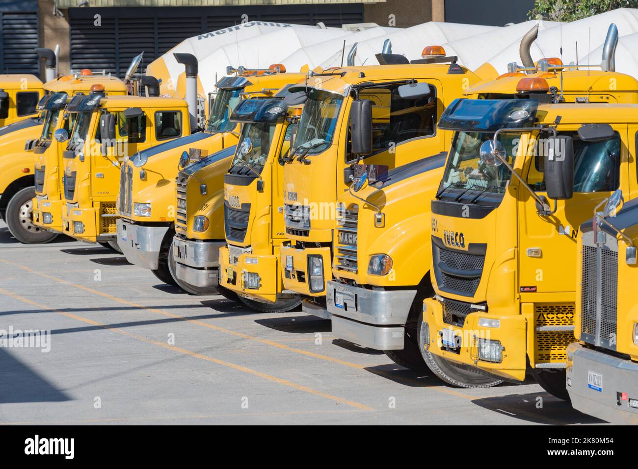 Una linea di betoniere gialle parcheggiate in un cantiere a Sydney, nuovo Galles del Sud, Australia Foto Stock