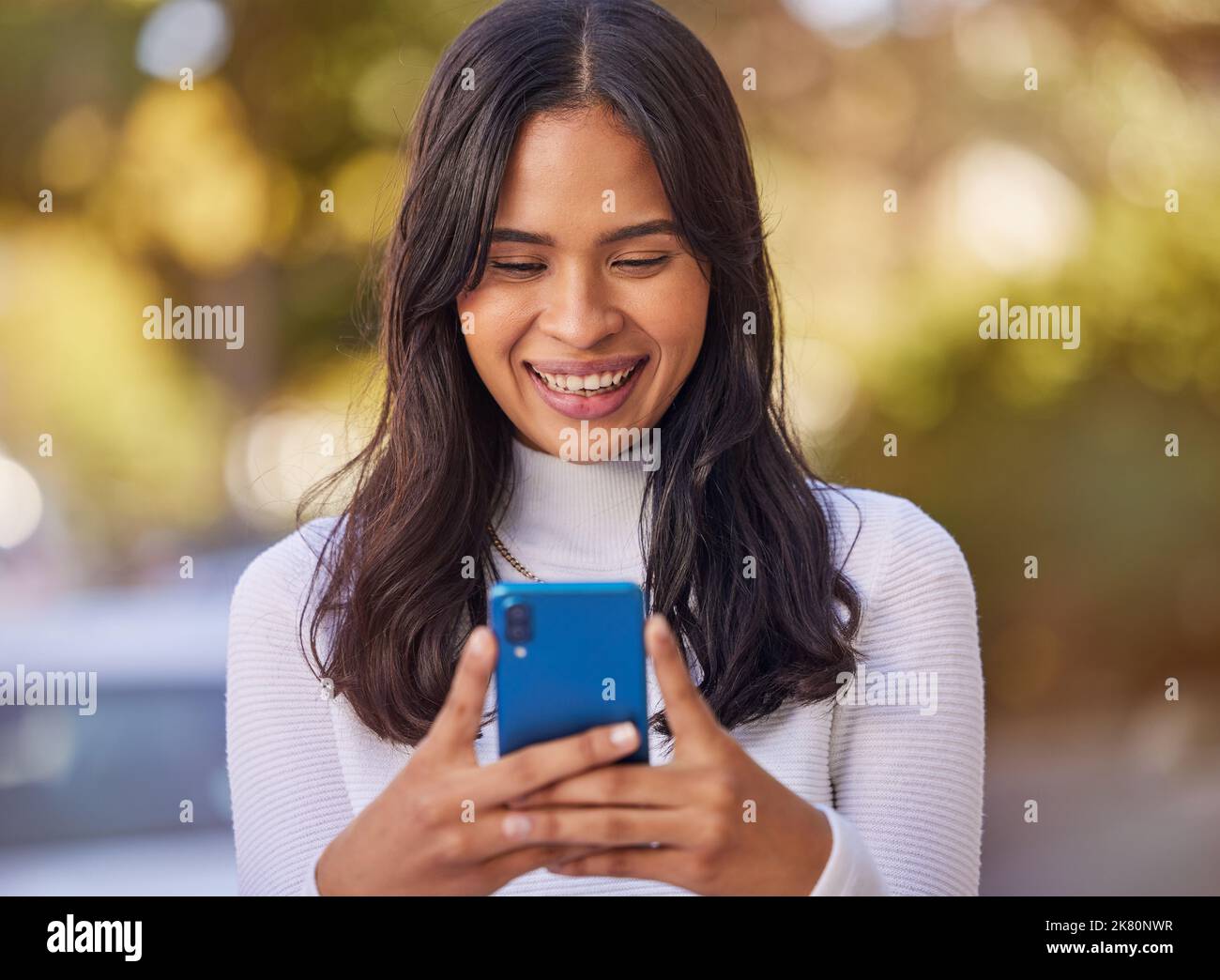 Social media, telefono e donna in città per affari, lavoro e lettura di comunicazione su un cellulare. Felice, sorridente e giovane ragazza che scrive su un cellulare Foto Stock