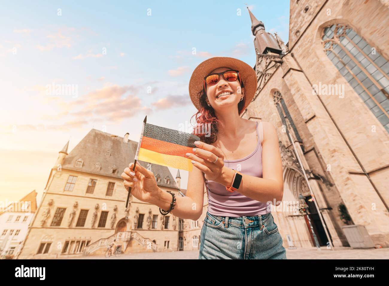 Una giovane ragazza asiatica felice con una bandiera tedesca al Municipio Rathaus di Osnabruck. Studiare la lingua all'estero e il concetto di viaggio Foto Stock
