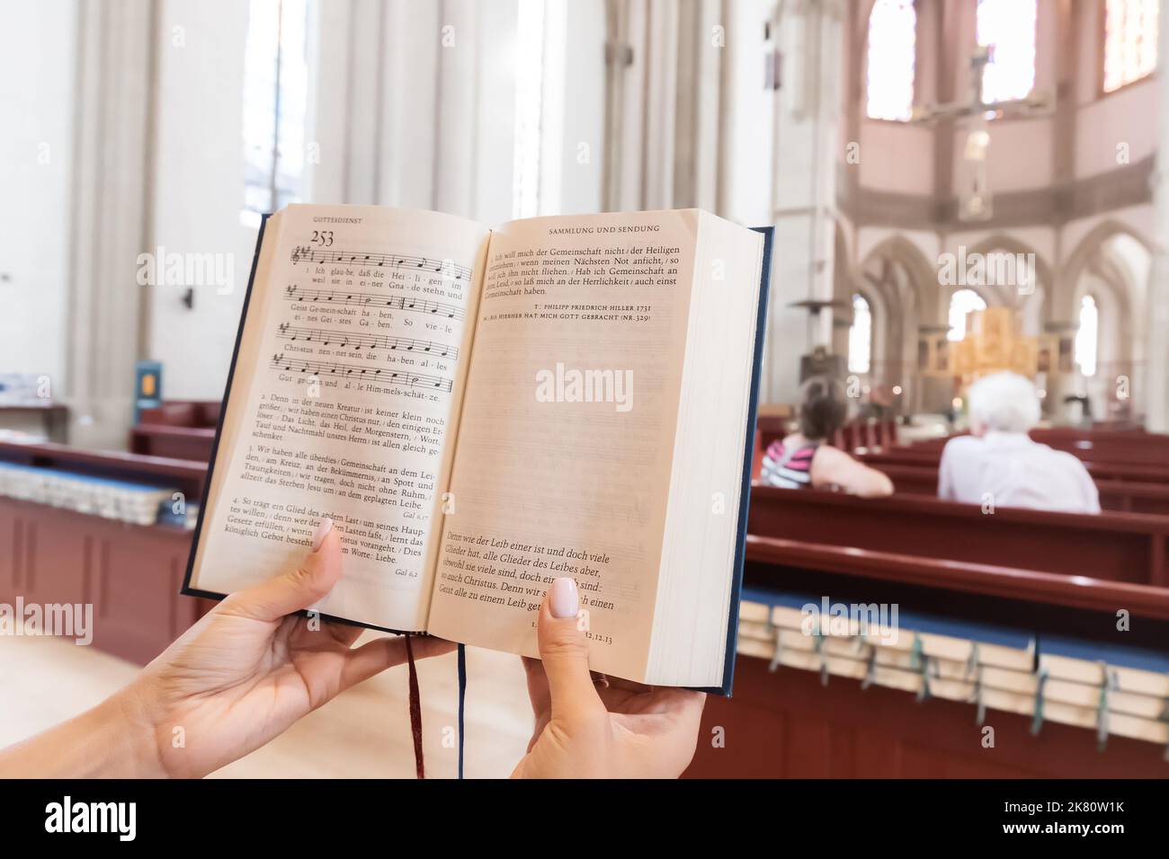 25 luglio 2022, Osnabruck, Germania: Donna che canta e legge i libri di canzoni del Vangelo in tedesco all'interno di una chiesa cattolica. Tempo libero e religioso edu Foto Stock