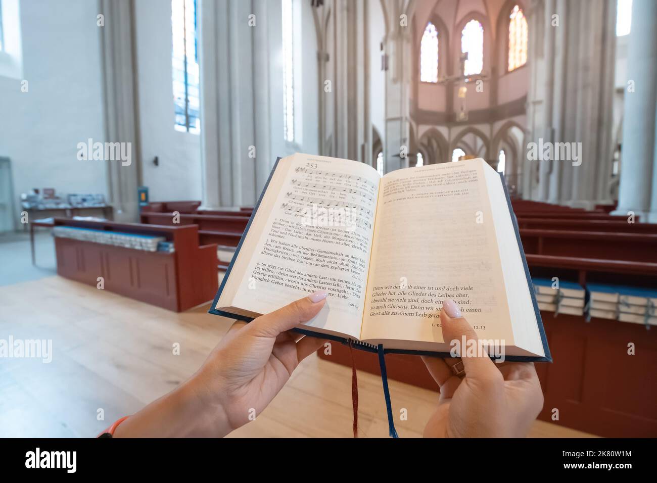 25 luglio 2022, Osnabruck, Germania: Donna che canta e legge i libri di canzoni del Vangelo in tedesco all'interno di una chiesa cattolica. Tempo libero e religioso edu Foto Stock