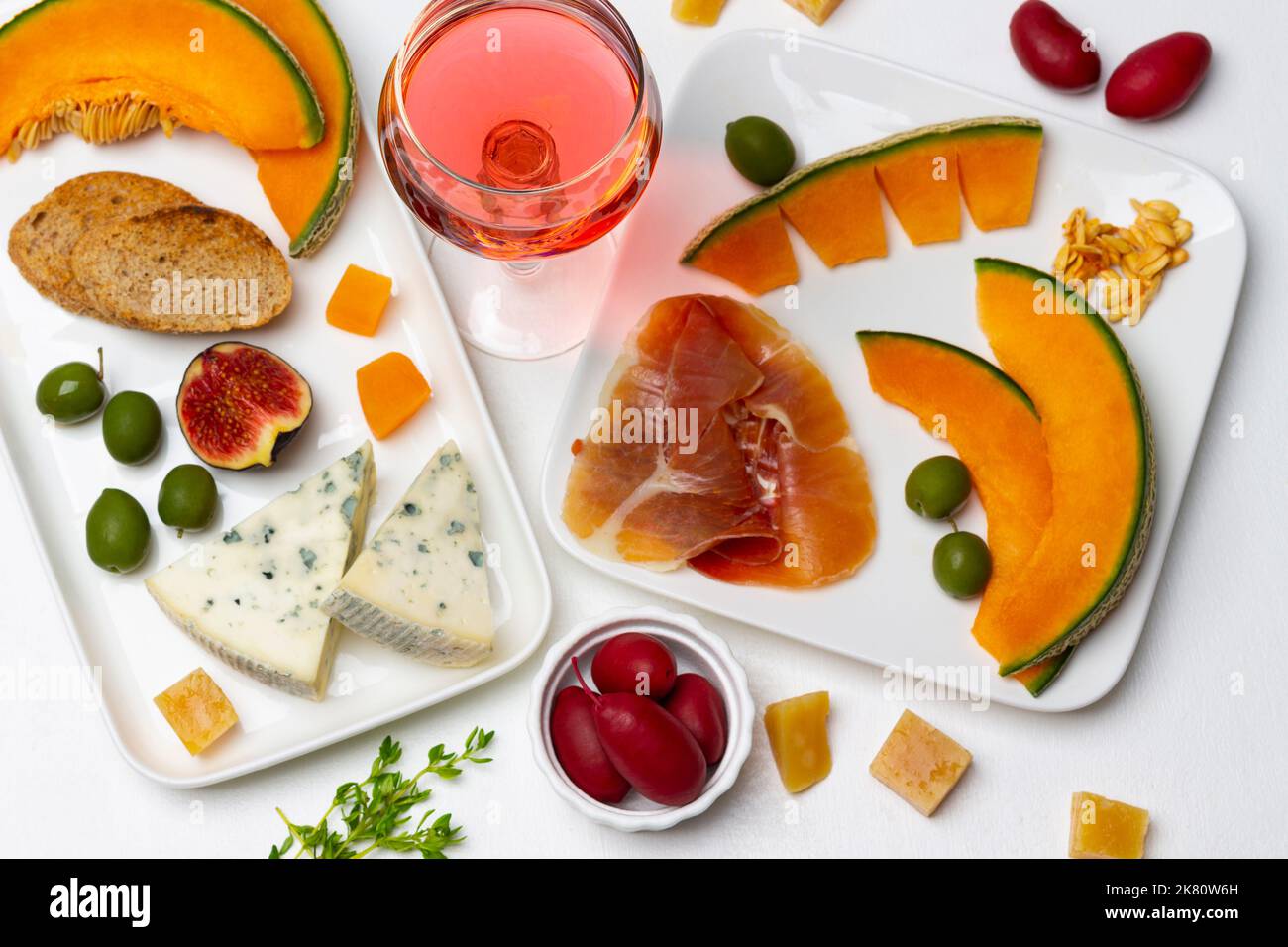 Aperitivo con olive, fettine di melone, fichi, formaggio e vino rosso. Giacitura piatta. Sfondo bianco. Foto Stock