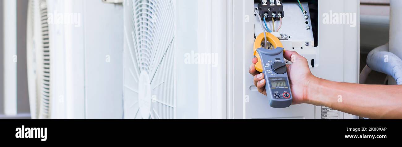 Riparatore del condizionatore d'aria che utilizza un contatore elettrico per controllare il funzionamento del condizionatore d'aria, concetto di manutenzione Foto Stock
