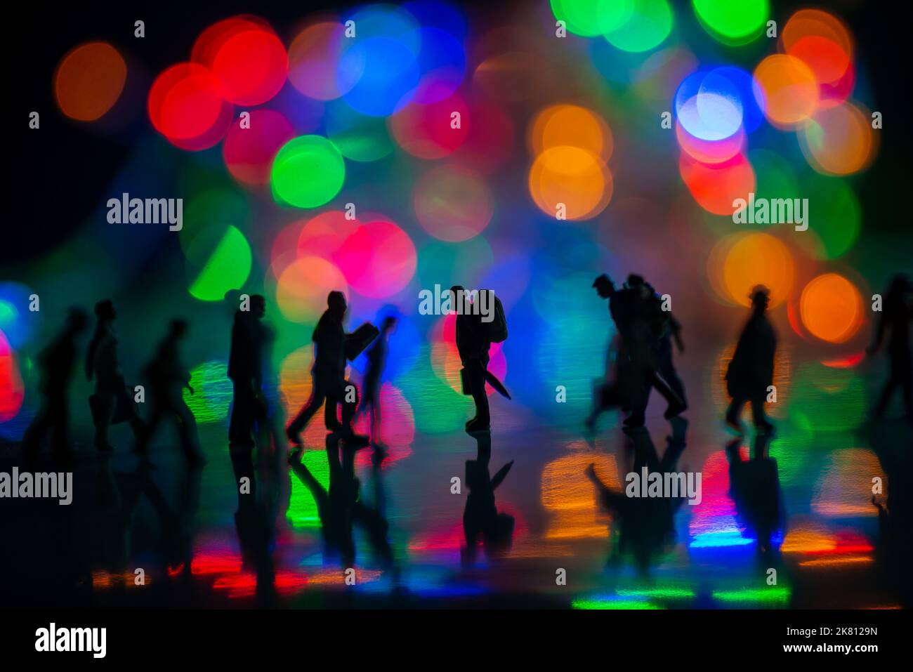 Mini persone giocattoli studio set up - Silhouette vista laterale di persone affollate a piedi con colorato sfondo bokeh sfocato. Concentratevi sull'uomo nel medio Foto Stock