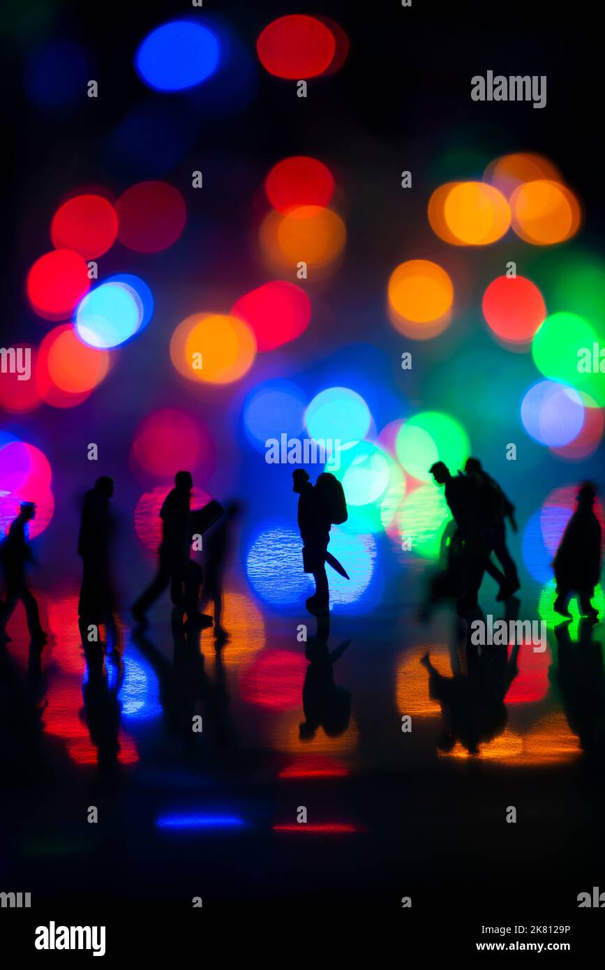 Mini persone giocattoli studio set up - Silhouette vista laterale di persone affollate a piedi con colorato sfondo bokeh sfocato. Concentratevi sull'uomo nel medio Foto Stock