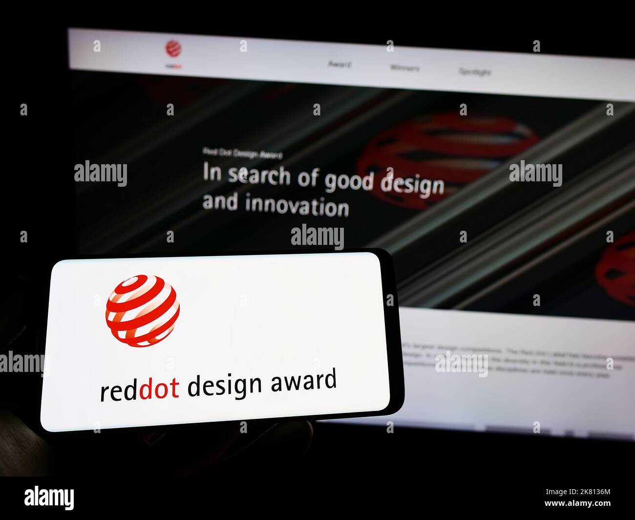 Persona che tiene il cellulare con il logo del premio internazionale tedesco Red Dot Design Award sullo schermo di fronte alla pagina web. Messa a fuoco sul display del telefono. Foto Stock
