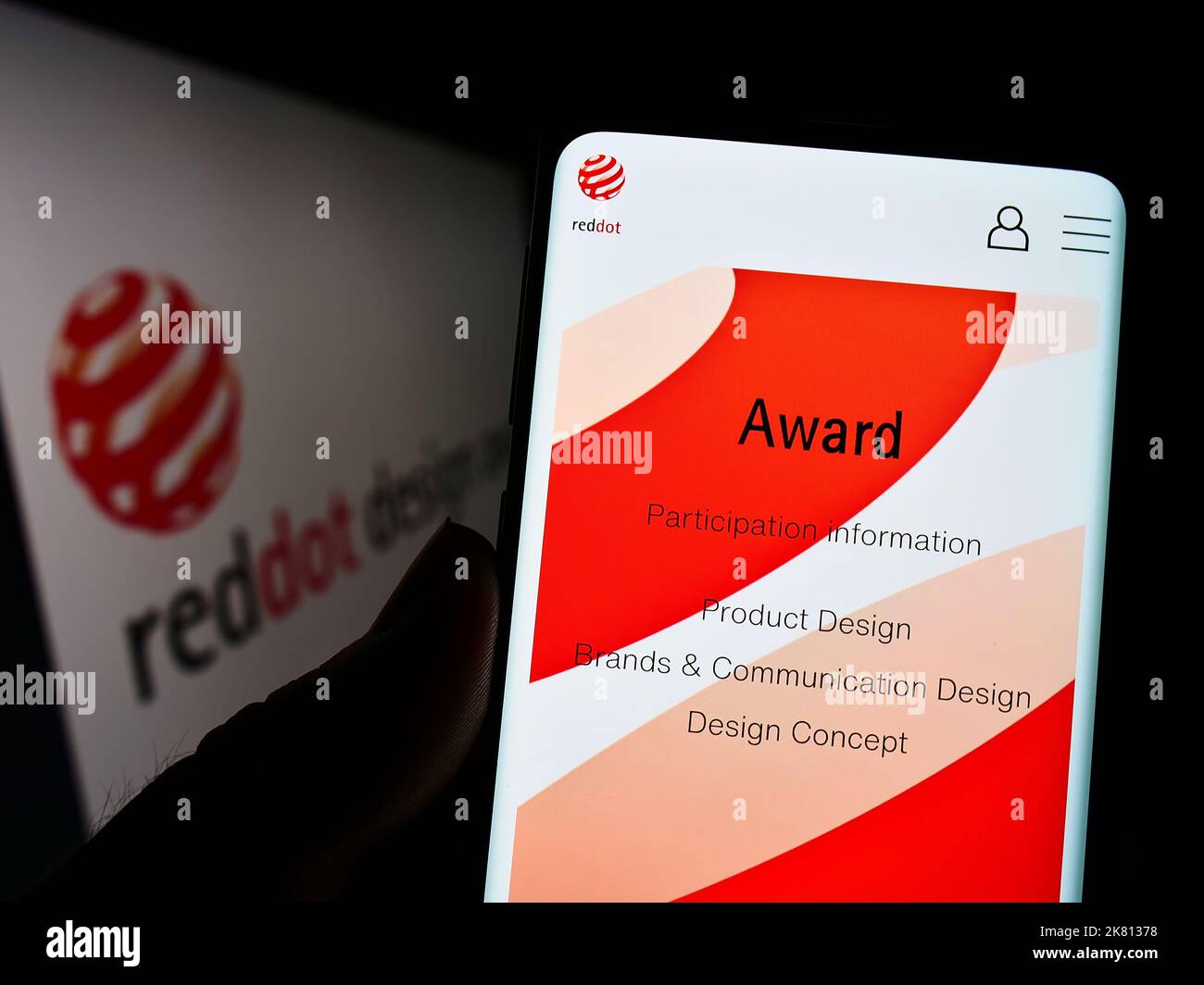 Persona che tiene il cellulare con il sito web del premio internazionale tedesco Red Dot Design Award sullo schermo con il logo. Messa a fuoco al centro del display del telefono. Foto Stock