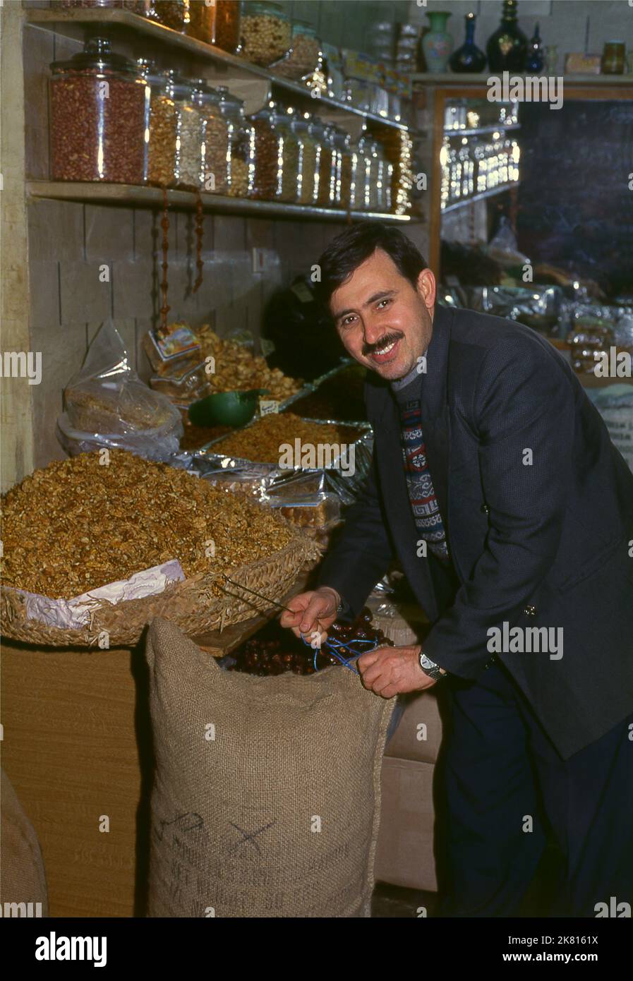 Siria: Vendita di frutta secca e noci nel grande bazar antico, Aleppo (1997). Il Grande Bazar di Aleppo (in arabo, suq o suq) fu ricostruito prima dai Mamelucchi egiziani che scacciarono i Mongoli, e poi, dopo il 1516, dai Turchi che incorporarono Aleppo nell'Impero Ottomano. Durante la guerra civile siriana, iniziata nel 2011, i suq storici di Aleppo subirono gravi danni. Aleppo, la seconda città della Siria è forse il più lungo insediamento continuamente abitato del mondo. Il suo nome arabo, Halab, è menzionato nei testi semitici del terzo millennio a.C.. Foto Stock