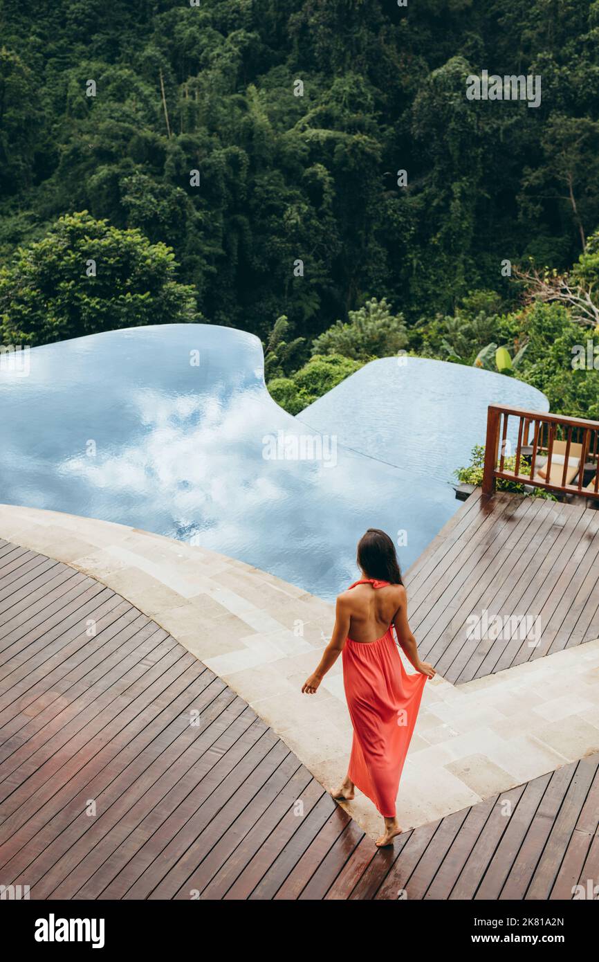 Scatto aereo bella giovane donna che cammina verso la piscina. Donna al resort di lusso a bordo piscina. Foto Stock
