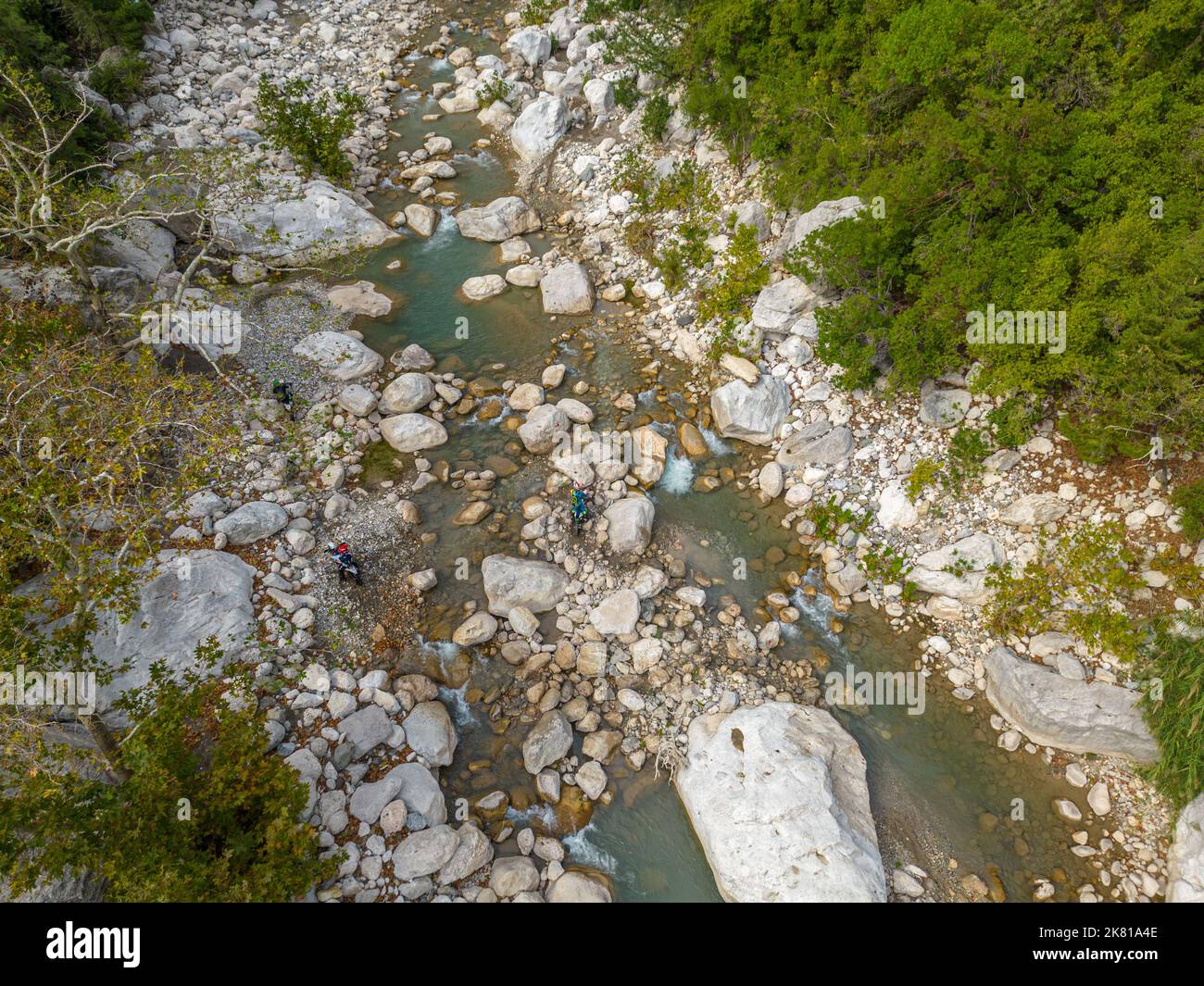 Motociclisti di fondo che cercano di superare le scogliere del fiume Foto Stock