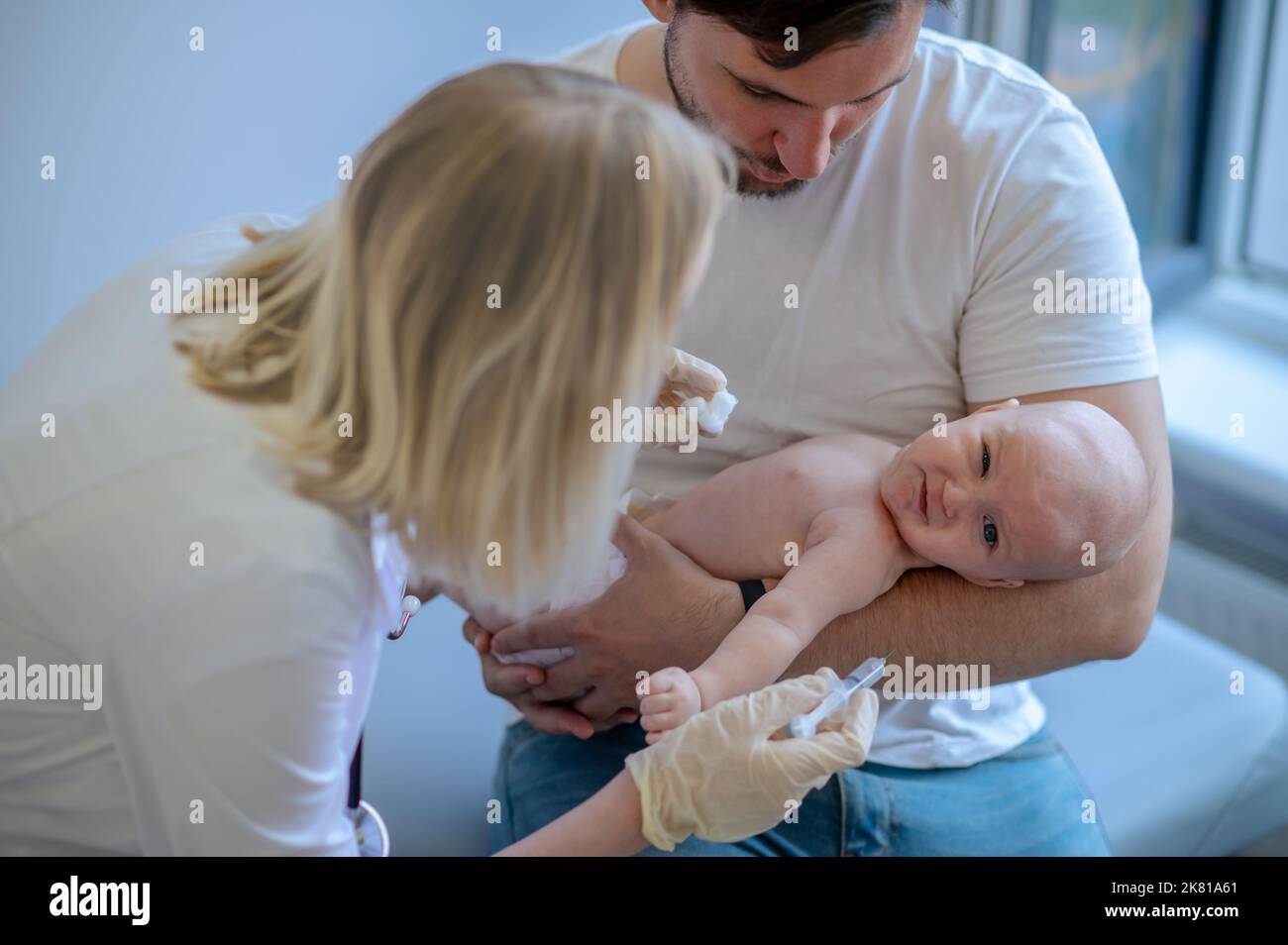 Medico pediatrico che si prepara a somministrare un'iniezione al neonato Foto Stock