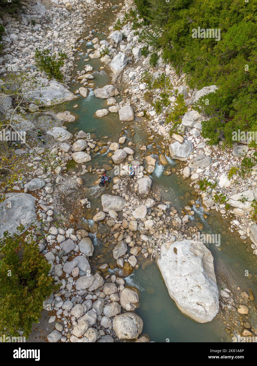 Motociclisti di fondo che cercano di superare le scogliere del fiume Foto Stock